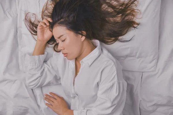 Mujer joven durmiendo en la cama. Vista superior de la mujer joven acostada durmiendo bien en la cama. dormir relajarse, joven sonriente hermosa dama se encuentra en la cama. relajante, durmiendo . — Foto de Stock