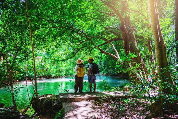 度假期间带着自然旅行背包的旅行夫妇。 情侣们一起旅行，在绿树成荫的丛林里放松，欣赏美丽的翡翠池塘。 旅游远足自然研究. — 图库照片