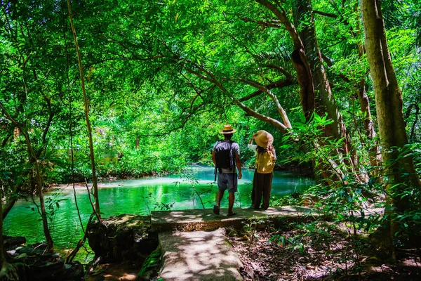 度假期间带着自然旅行背包的旅行夫妇。 情侣们一起旅行，在绿树成荫的丛林里放松，欣赏美丽的翡翠池塘。 旅游远足自然研究. — 图库照片