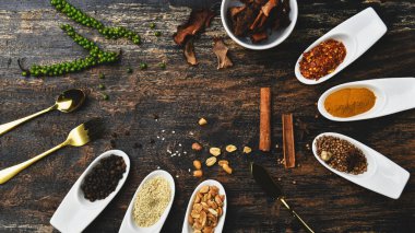 Ahşap masada çeşitli renkli otlar ve baharatlar. Baharat ve bitkilerin en üst görüntüsü. Baharatlar ve otlar ahşap masa arkasında..