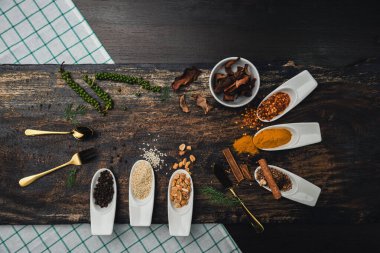 Ahşap masada çeşitli renkli otlar ve baharatlar. Baharat ve bitkilerin en üst görüntüsü. Baharatlar ve otlar ahşap masa arkasında..