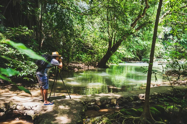 Erkekler yürüyüş yapıyor, tatillerde doğanın fotoğraflarını çekiyor. Ormanda Doğa Araştırması. Ormanda yürüyüş yapan yürüyüşçüler. Yağmur ormanları boyunca seyahat ediyorum. Tropik bir ormanda seyahat eden sırt çantalı bir adam..