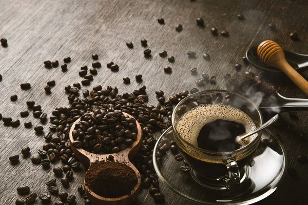 Bruna kaffebönor och en kopp varmt kaffe på ett träbord med honung. Trä bakgrund och espresso och bönor. Toppvy med kopieringsutrymme för din text. — Stockfoto