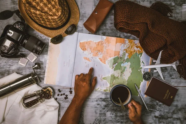 Turista planejamento de férias com a ajuda de mapa do mundo e bússola ao longo e xícara de café com moedor de café com outros acessórios de viagem. A preparar-se para viajar. Viagens planejamento conceito férias com mapa. Verão . — Fotografia de Stock