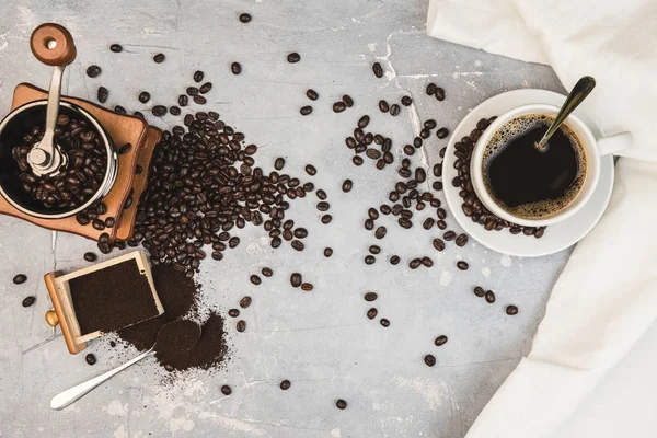 Kaffekopp, med kaffekvarn och kaffebönor med malet pulver på bordet. Ovanifrån Varmt kaffe på ett gammalt köksbord. bakgrund koncept Kaffekopp och kaffekvarn med andra tillbehör. — Stockfoto