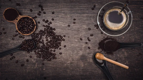 Bruna kaffebönor och en kopp varmt kaffe på ett träbord med honung. Trä bakgrund och espresso och bönor. Toppvy med kopieringsutrymme för din text. — Stockfoto