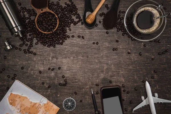 Bruna kaffebönor och en kopp varmt kaffe på ett träbord. Begreppet resa med karta. Dags att koppla av med en kopp gott kaffe. Ovanifrån kopieringsutrymme för din text. — Stockfoto