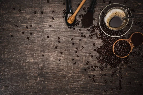 Bruna kaffebönor och en kopp varmt kaffe på ett träbord med honung. Trä bakgrund och espresso och bönor. Toppvy med kopieringsutrymme för din text. — Stockfoto