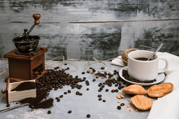 Coffee cup, with coffee grinder and coffee beans with ground powder on table. Top view Hot coffee and pastries on a old kitchen table. background concept Coffee cup and coffee grinder with other accessories. — Stock Photo, Image