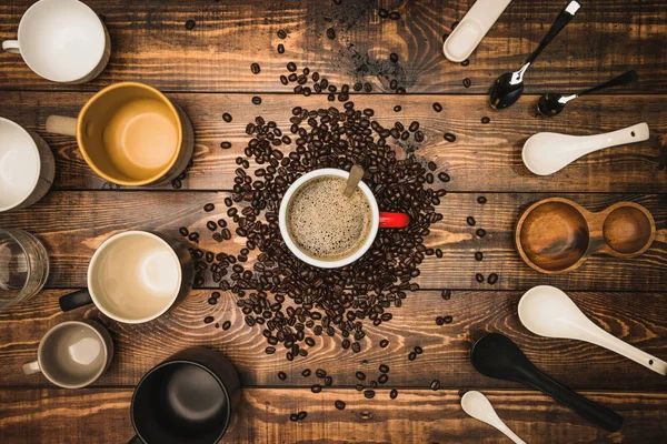 Många koppar kaffe med bönor på träbord, ovanifrån. Platt låg komposition med koppar kaffe på bakgrunden Gammal trä korn. Fotografering av mat, dryck. — Stockfoto