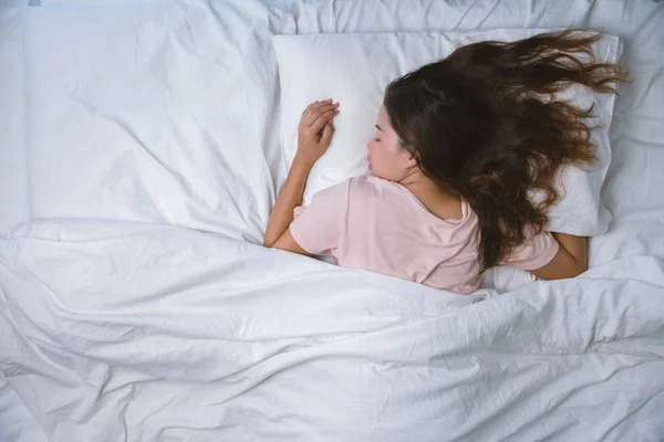 Девочка-подросток спит. концепция хорошего ночного сна. Девушка в пижаме спит на кровати в белой комнате утром. теплый тон . — стоковое фото