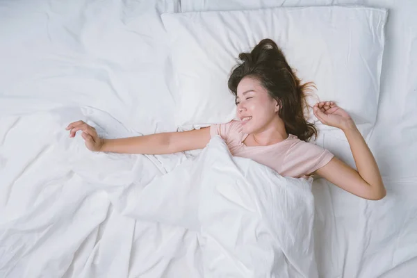 Teenager-Mädchen schläft ausgeruht. Gute Nachtruhe Konzept. Mädchen im Pyjama schläft morgens auf einem Bett in einem weißen Zimmer. warmer Ton. — Stockfoto