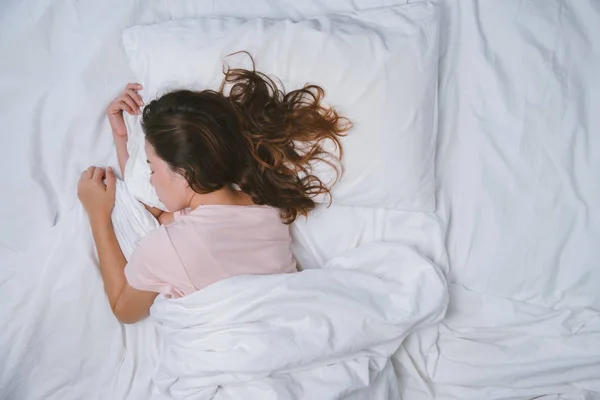Teenager-Mädchen schläft ausgeruht. Gute Nachtruhe Konzept. Mädchen im Pyjama schläft morgens auf einem Bett in einem weißen Zimmer. warmer Ton. — Stockfoto