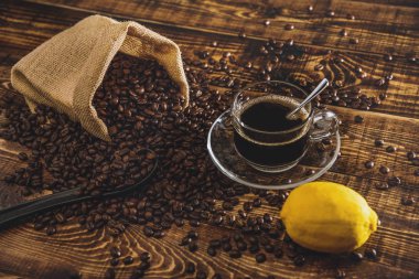 Kahve fincanı ve fasulye eski mutfak masasında. Metnin için kopyalama alanı olan üst görünüm. Kahve poşeti ve ahşap masada limonlar. Sade kahve çekirdeği. Espresso.