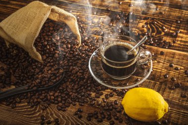 Kahve fincanı ve fasulye eski mutfak masasında. Metnin için kopyalama alanı olan üst görünüm. Kahve poşeti ve ahşap masada limonlar. Sade kahve çekirdeği. Espresso.