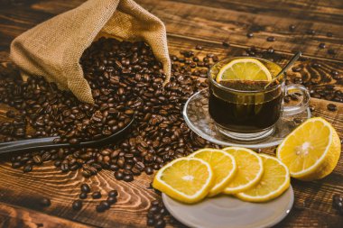 Kahve fincanı ve fasulye eski mutfak masasında. Metnin için kopyalama alanı olan üst görünüm. Kahve poşeti ve dilimlenmiş limonlu ahşap masa. Siyah kahve çekirdekleri.