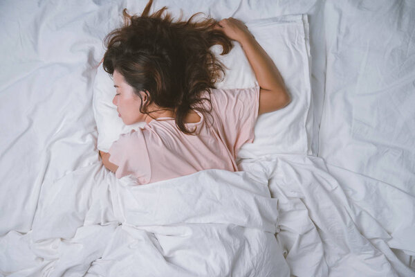 Teenage girl sleeping resting. good night sleep concept. Girl wearing a pajama sleep on a bed in a white room in the morning. warm tone.