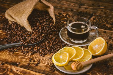 Kahve fincanı ve fasulye eski mutfak masasında. Metnin için kopyalama alanı olan üst görünüm. Kahve poşeti ve dilimlenmiş limonlu ahşap masa. Siyah kahve çekirdekleri.