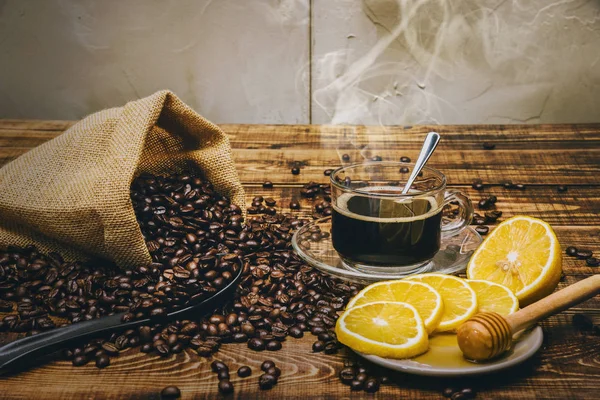 Kaffekopp och bönor på gammalt köksbord. Toppvy med kopieringsutrymme för din text. kaffesäck och med skivade citroner på träbord. Svarta kaffebönor. — Stockfoto