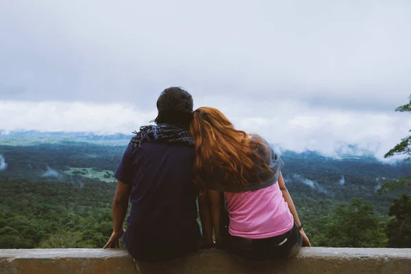 Casal sentado na frente de uma montanha olhando para o horizonte no feriado. Descontrai. Sentado relaxe no penhasco de Mountain Rock. Natureza das florestas de montanha na Tailândia . — Fotografia de Stock