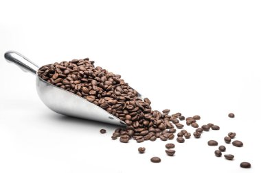 Kaşık kaşık kahve kepçesi ve kahve çekirdekleri beyaz arka planda kavrulmuş ve metin için fotokopi alanı var.