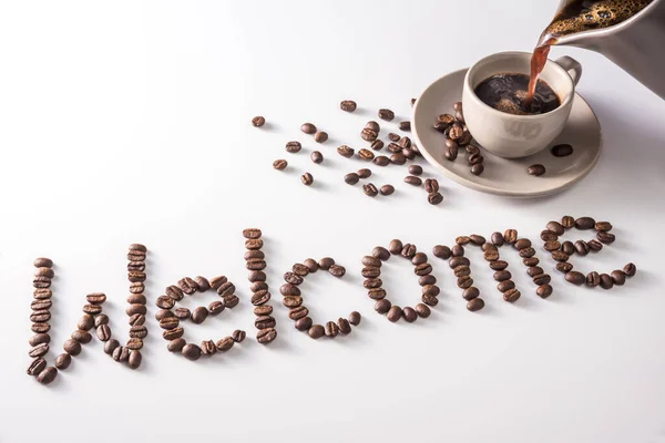 Coffee cup and text made of coffee beans, isolated on white. text the word Welcome made of coffee beans. font