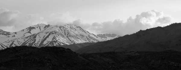Schneebedeckte Berge Mit Dunklen Trockenen Kargen Bergen Vordergrund Unter Bewölktem — Stockfoto