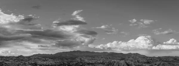 ジョシュアツリー国立公園の岩のキャンプ場の黒と白のパノラマ 雲と山と下の岩の形成でいっぱいの劇的な空 — ストック写真