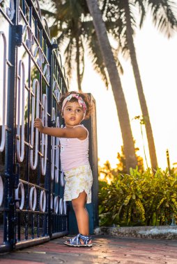 Oyuncak Hintli kız çocuk / çocuk / bebek saç bandı takıyor, bisiklet / üç tekerlekli bisikletle oynuyor. Çocuk neşeli ifadeler takınıyor