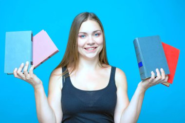 2 olan oldukça beyaz kadın mavi arka plan üzerinde duruyor gülen her el kitapları. Siyah saçlı ve mavi gözlü. Kadar rahat (siyah bluz), hafif makyaj giyiyor. İzole, stüdyo, kopya alanı.