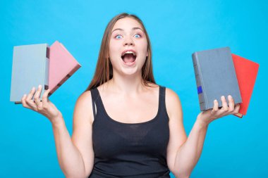 bir çığlık açılan ağzına oung beyaz kadınla kitapları her iki elinde tutar. İzole bue arka plan, studio, model üzerinde. Eğitim kavramı komplikasyonları. Komik, mizah resim. Kopya alanı