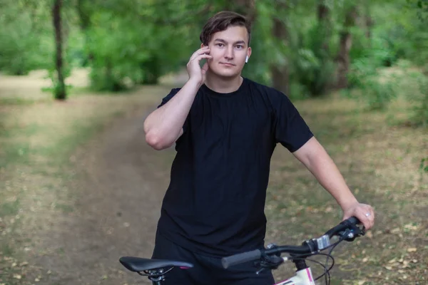 Viehättävä Nuori Valkoihoinen Mies Pitää Matkapuhelinta Polkupyörää Vihreässä Puistossa Valkoiset — kuvapankkivalokuva