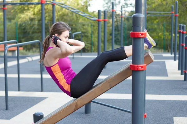 Park spor zemin genç kafkas kadın egzersiz programı. Kız karın excersise, siyah ve Lila spor yapar. Beyaz kulaklık, koruyucu eldiven. Gerçek kadın sabah eğitim. Açık, kopya alanı. 