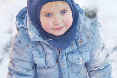 Kış giysileri ve şapka (başlık) kış arka plan üzerinde parlak mavi gözlü sevimli beyaz liittle çocuk. Sağlıklı çocukluk. Açık havada, Kış etkinliği. Uzay kopyalayın, portre kadar yakın. 