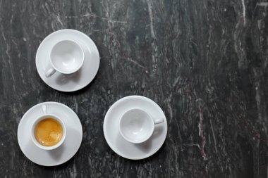 Üstten görünüm leylak mermer zemin üzerine üç küçük kahve fincan üzerinde. Bir kahve, iki tane boş. Kapalı, alanı Kopyala.