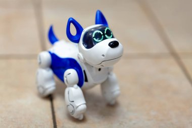 Seçici odak bir bej seramik zemin arka plan üzerinde etkileşimli elektronik oyuncak köpek yavrusu. Yüksek teknoloji kavramı, gelecek, elektronik ev evde beslenen hayvan. Kapalı, uzay kopyalayın, yakın çekim. 