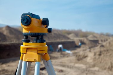 Surveyor inşaatçılar için özel aygıt (düzey), Jeodezi cihazları yakın bir yere çalışma arka plan bulanık kişilerle önünde. Açık havada, kopya alanı.