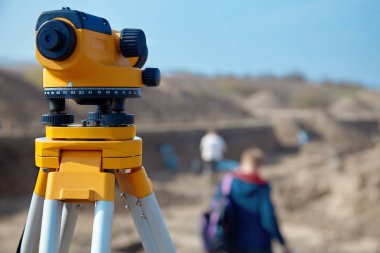 Surveyor inşaatçılar için özel aygıt (düzey), Jeodezi cihazları yakın bir yere çalışma arka plan bulanık kişilerle önünde. Açık havada, kopya alanı.