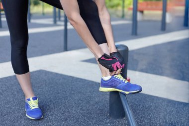 Erkek spor giyim ve koruyucu eldiven çalıştırmak bir koşu veya diğer fitness için hazırlanıyor parlak spor ayakkabı bağları. Sabah egzersiz açık havada arka plan üzerinde. Kopya alanı. 