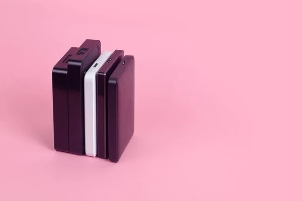 Some external hard drives for storing data, backups and security information. Pink background, isolated, copy space.