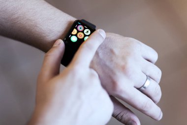 Rostov-on-Don, Rusya - Aralık 2018: Ekranda uygulama bulutu olan modern akıllı saat giyen adam eli. Giyilebilir gadget konsepti. İç mekanlar, kopyalama alanı.