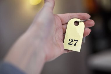 Otel odasının anahtarını tutan kadın eli. Seçici odaklama, iç mekanlar, kopyalama alanı. 
