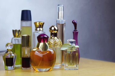 Ahşap masaüzerinde bazı renkli parfüm şişeleri. Eski vintage parfümler. Seçici odak, gri arka plan, iç mekan, kopyalama alanı.