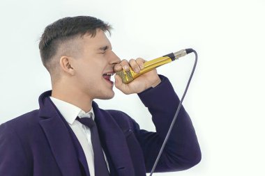 Genç yakışıklı beyaz adam kapalı gözleri ve tutku ile altın mikrofona söylüyor. Parti veya karaore vokal kavramı. Stüdyo, ışık arka plan, kopyalama alanı.