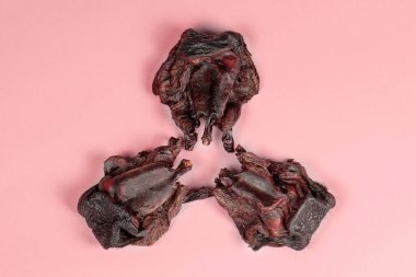 Üç parça kurutulmuş sığır burnu. Kuru köpek maması gibi kullanılıyor. Kenarlarında küçük kürkleri var. Evcil hayvanlar için ev yapımı doğal yemek. Kapalı alan, pembe arkaplan, kapat, kopyala.