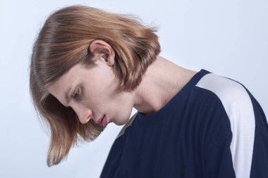 Kafası aşağıda yakışıklı beyaz bir adam, açık gözlü ve sarı saçlı, yüzünde üzgün bir ifade var. Melankoli ya da depresyon konsepti, olumsuz duygular. Beyaz arkaplan, alanı kopyala.