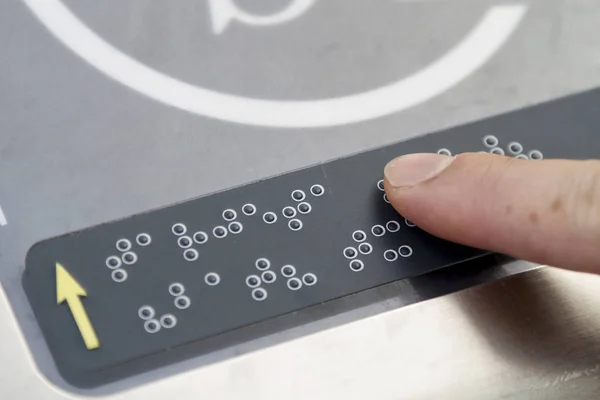 Braille kamuya açık bir yerde parmaklarıyla okuma bir kişi
