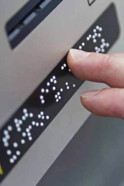 Braille kamuya açık bir yerde parmaklarıyla okuma bir kişi