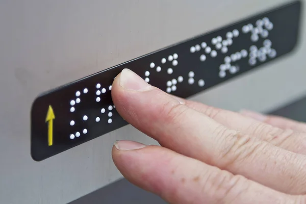 Braille kamuya açık bir yerde parmaklarıyla okuma bir kişi