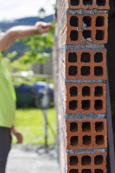 A man building a brick wall and a window